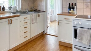 Una cocina con armarios blancos, encimeras de madera y horno empotrado.