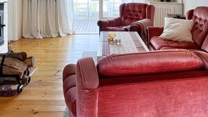 Una sala de estar acogedora con un sofá rojo, una mesa de centro de madera y una chimenea.
