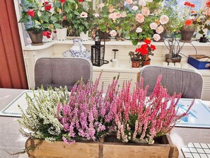 A table with a floral centerpiece, a window with potted plants, and a chair. - 4 Star Holiday Home in Enskede (Enskede)