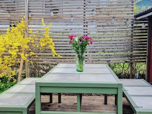 Una mesa de madera con un florero frente a una valla de madera.
