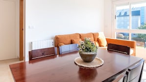 Ein Essbereich mit Holztisch, Blumenvase und einer Couch mit Kissen.
