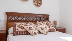 Ein Bett mit Holz-Kopfteil, zwei Wandgestaltungen und gemusterte Kissen.