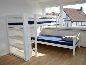 Een stapelbed met uitzicht op een gebouw met rode dakpannen.