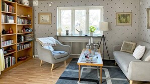 A cozy living room with a bookshelf, a grey armchair, a sofa, and a coffee table. - 4 Person Holiday Home in Hammenhog-by Traum (Hammenhög)