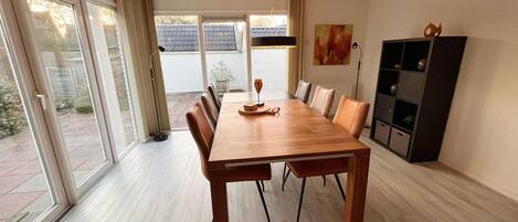 A spacious dining area with a long wooden table, multiple chairs, and a modern black cabinet.