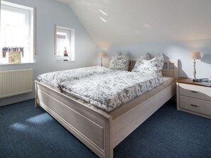 A bedroom with a bed, bedside tables, a window, and a radiator.
