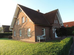 A two-story brick house with a sloped roof, a front porch, and a well-maintained lawn.