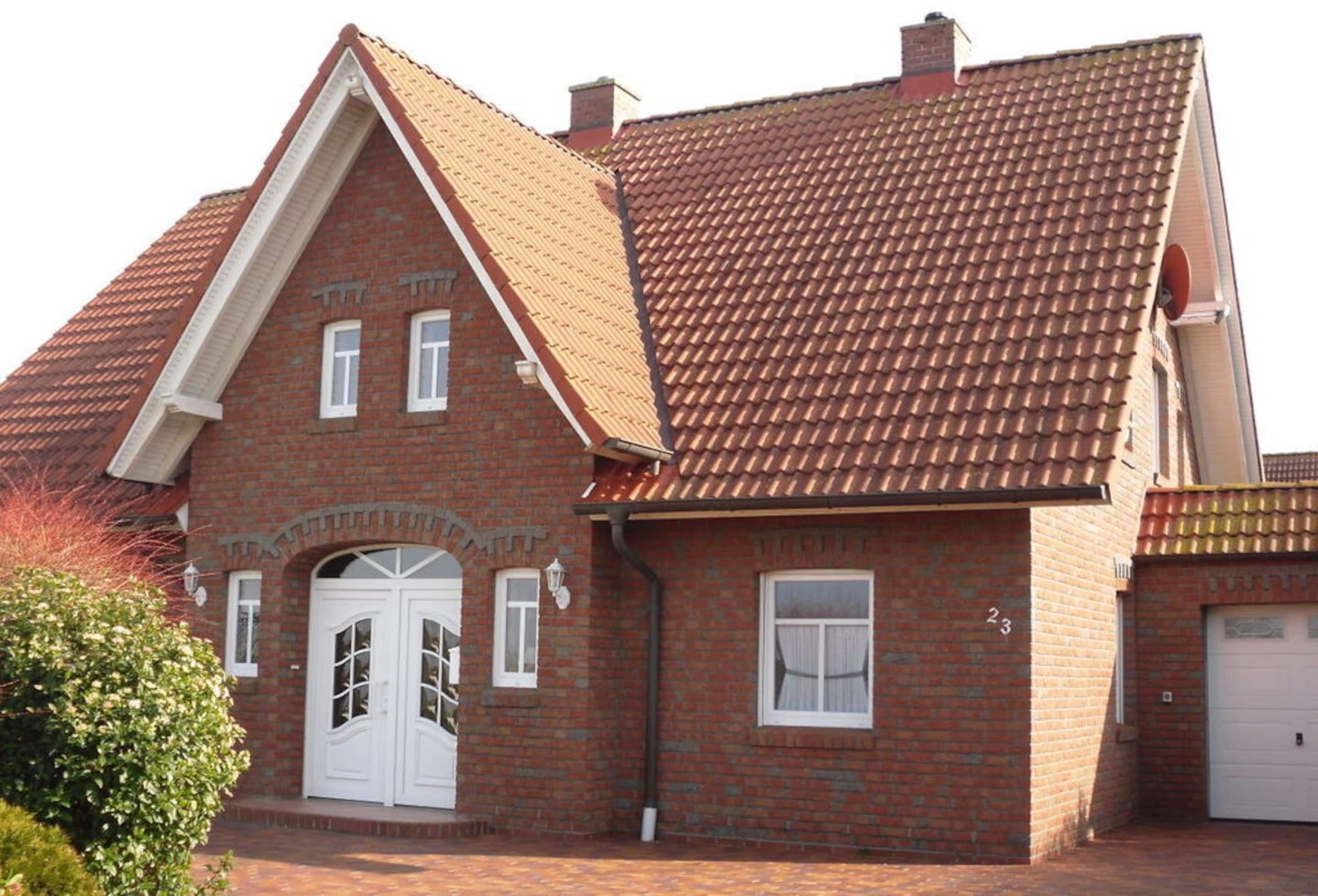 A two-story brick house with a red-tiled roof, a white front door, and a garage.