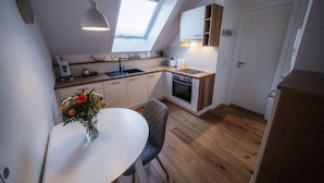 A compact kitchen with a skylight, a dining table with a vase of flowers, and a wooden floor. - Holiday Apartment Swallow's Nest (Eichstetten am Kaiserstuhl)