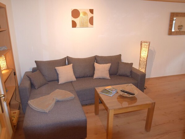 A living room with a sofa, a coffee table, and a wall-mounted artwork.