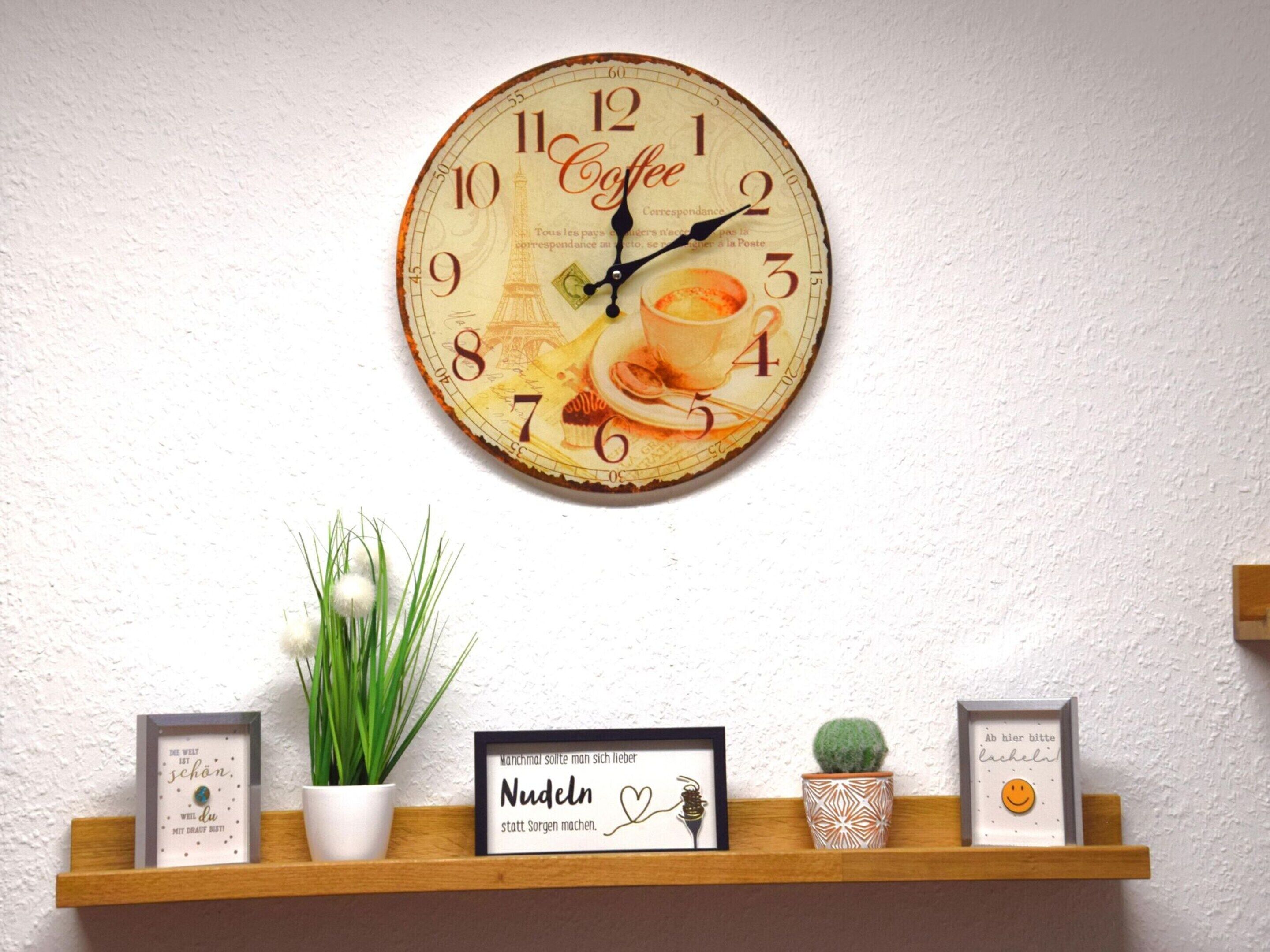 A wall clock with a coffee theme, a shelf with decorative items, and a small potted plant.
