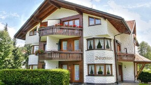 Un immeuble à plusieurs étages, à la façade blanche et aux balcons en bois, sur lequel on peut lire l’inscription « Bärenbush ».