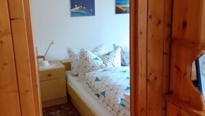 Une chambre avec une arche en bois, un lit recouvert d’une literie à motifs, une table de chevet avec une lampe et deux tableaux accrochés au mur.