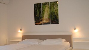 A neatly made bed with white linens, a headboard, and two bedside lamps. - Mesmerising Apartment in Punat (Punat)