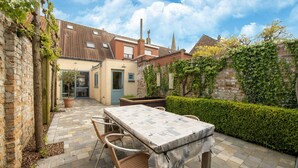 A patio area with a table and chairs, a brick wall, and a hedge. - Seaside Charm & Privacy (Nieuwpoort)