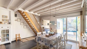 A dining area with a wooden staircase, a table with a patterned tablecloth, and a view of the outside through a glass door. - Seaside Charm & Privacy (Nieuwpoort)
