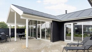 A covered patio area with outdoor furniture and a glass enclosure. - 5 Star Holiday Home in Albaek (Aalbaek)
