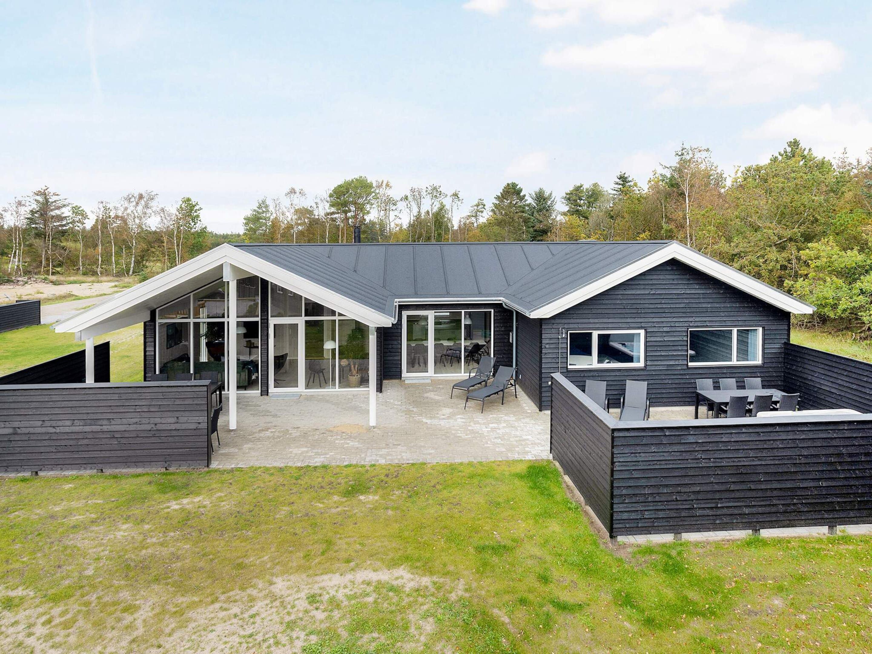 A modern house with a large patio, a covered outdoor area, and a view of the surrounding landscape.