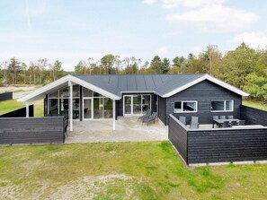 Une maison moderne dotée d’un grand patio, d’un espace extérieur couvert et offrant une vue sur le paysage environnant.