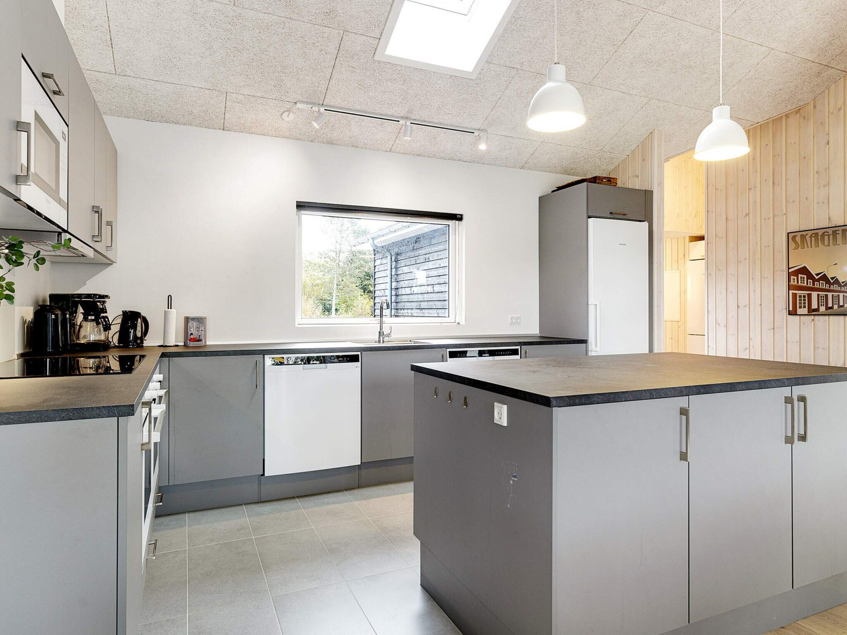 A modern kitchen with a central island, built-in appliances, and a window providing natural light.