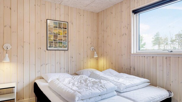 A room with a bed, a nightstand, a wall-mounted picture, and a window. - 5 Star Holiday Home in Albaek (Aalbaek)