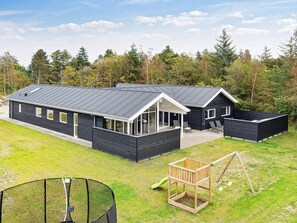 Un chalet moderne à deux étages, doté d’un toit plat, de grandes fenêtres et d’un patio couvert.