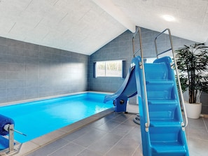 An indoor swimming pool with a blue slide, tiled walls, and a potted plant. - 5 Star Holiday Home in Albaek (Aalbaek)