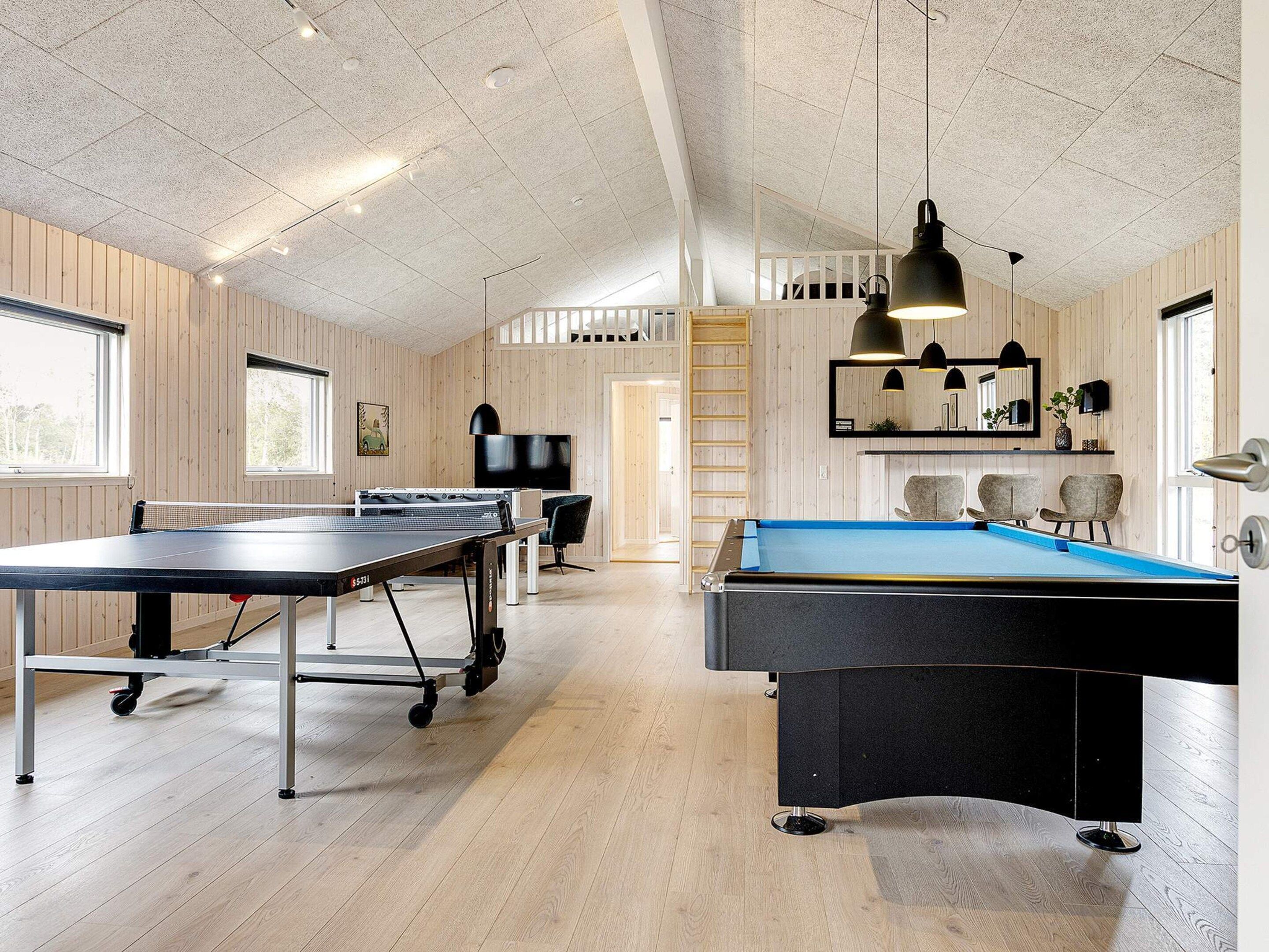A spacious indoor recreational area with a ping pong table, pool table, and seating area.