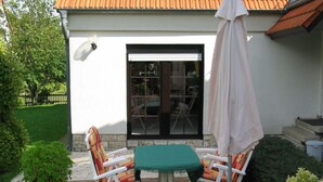 Eine Terrassengruppe mit Tisch, Stühlen, einem Blumentopf und einem weißen Sonnenschirm.