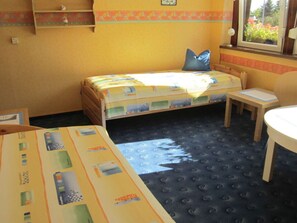 Une petite chambre accueillante, avec un lit simple, une petite table et une fenêtre donnant sur un paysage verdoyant.