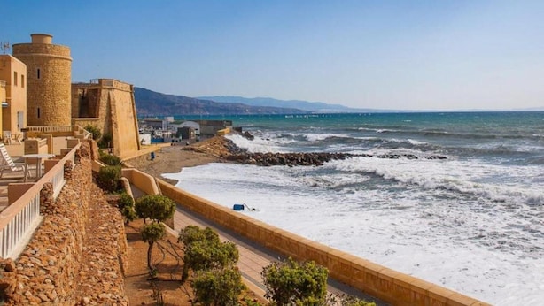 A coastal view with a stone building and a beach. - Apartment in Roquetas Near the Beach (Roquetas de Mar)