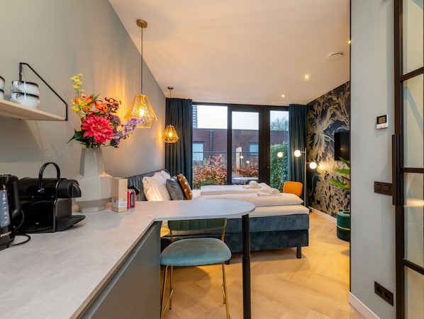 Una habitación de hotel moderna con kitchenette, comedor y sofá cama.