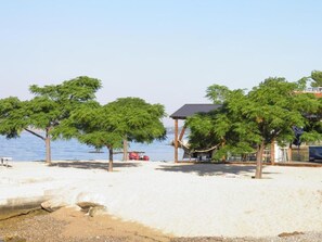 A beach with trees, a gazebo, and a building by the water. - Sunny Pool Apartments - One Bedroom Apartment (Jasenice)