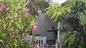 A courtyard with a white railing, a stone pathway, and lush green plants. - Sunny Pool Apartments - One Bedroom Apartment (Jasenice)