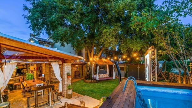 A backyard with a pool, wooden deck, outdoor seating, and string lights. - Vakantiehuis Loris (Marcana)