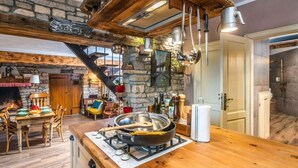 A rustic kitchen with a wooden table, a stove, and hanging pots. - Vakantiehuis Loris (Marcana)