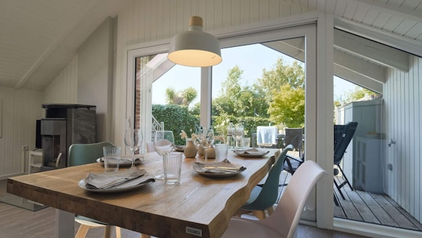 Un espace repas comprenant une table en bois, des chaises et un luminaire suspendu.