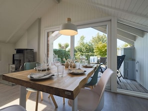 Un espace repas comprenant une table en bois, des chaises et un luminaire suspendu.