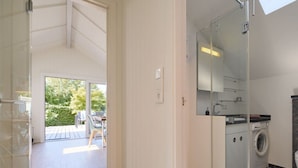 Une salle de bain moderne dotée d’une douche à parois de verre, d’un lave-linge encastré et d’un grand miroir.