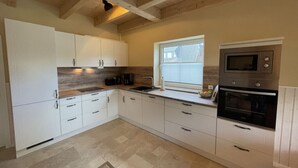 Een moderne keuken met witte kasten, een ingebouwde oven en een magnetron.