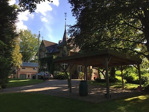 A traditional building with a covered outdoor area, surrounded by trees and a clear sky. - Das-zauberlig-ferienhaus (Gluecksburg)