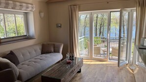 A spacious living room with a large window, a sofa, and a wooden coffee table.