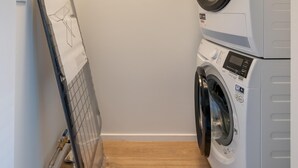 A laundry room with stacked washers and dryers, a drying rack, and a wooden floor. - Modern Renovated Apartment in the Heart of Sneek (Sneek)