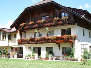 Un edificio a due piani con un balcone decorato con vasi di piante e fiori.