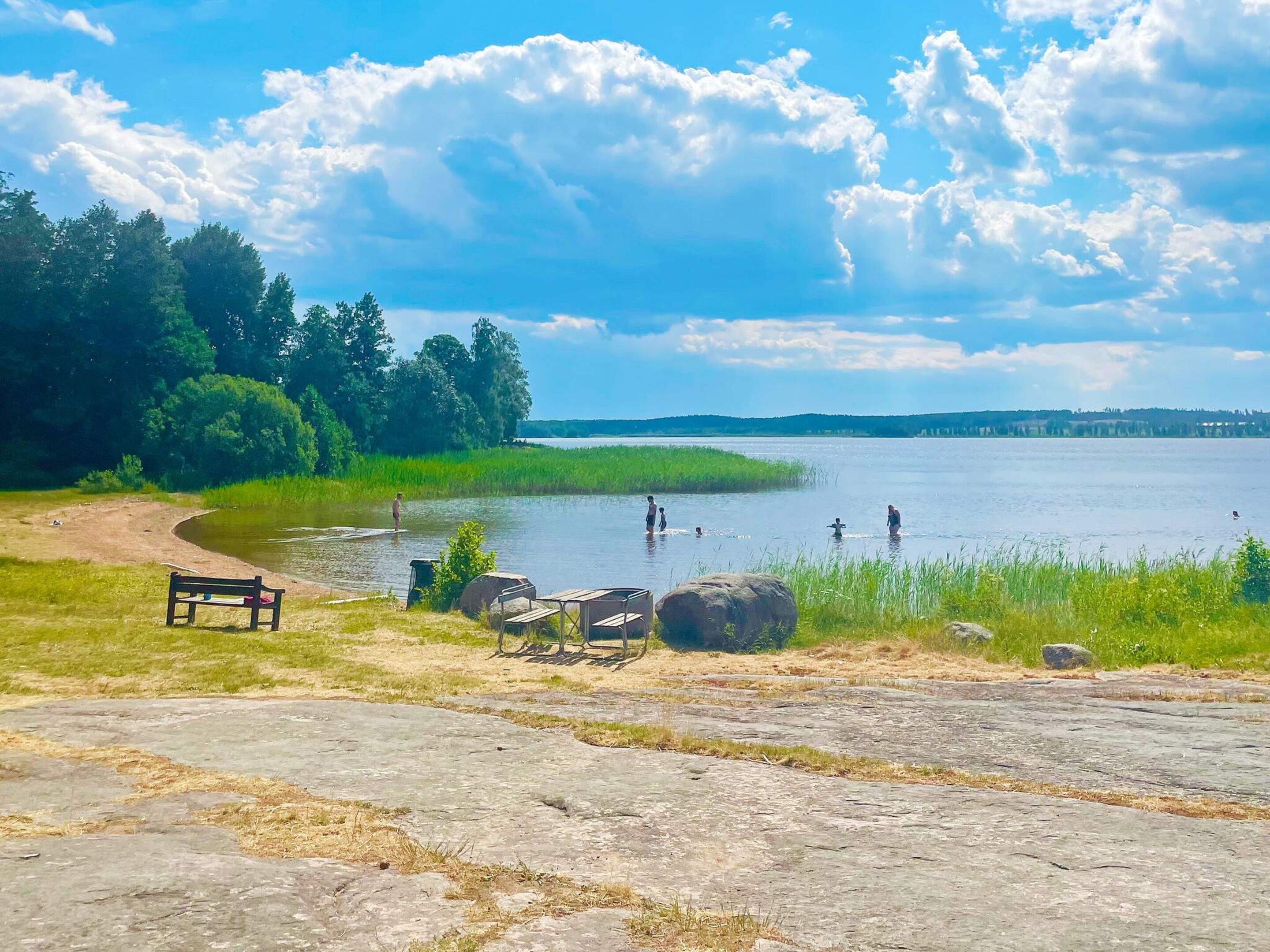 Un endroit au bord du lac avec un banc, une table de pique-nique et des rochers.