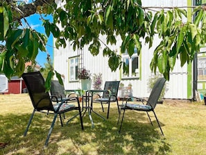 An outdoor seating area with four chairs and a table, surrounded by a white building with windows and a door. - 4 Person Holiday Home in Sodra vi (Sodra Vi)