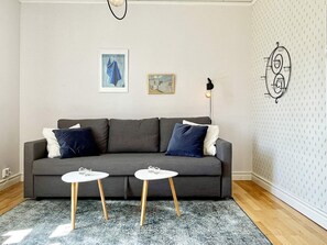 A living room with a grey sofa, two small white tables, and a patterned rug. - 4 Person Holiday Home in Sodra vi (Sodra Vi)
