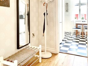 A hallway with a coat rack, a bench, and a checkered floor leading to a dining area with a table and chairs. - 4 Person Holiday Home in Sodra vi (Sodra Vi)