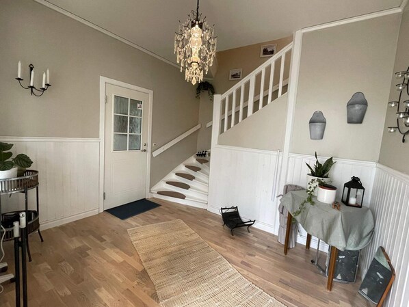 A staircase with white railings leading to an upper floor, a chandelier hanging from the ceiling, and a small table with a plant on the landing. - 4 Person Holiday Home in Sodra vi (Sodra Vi)