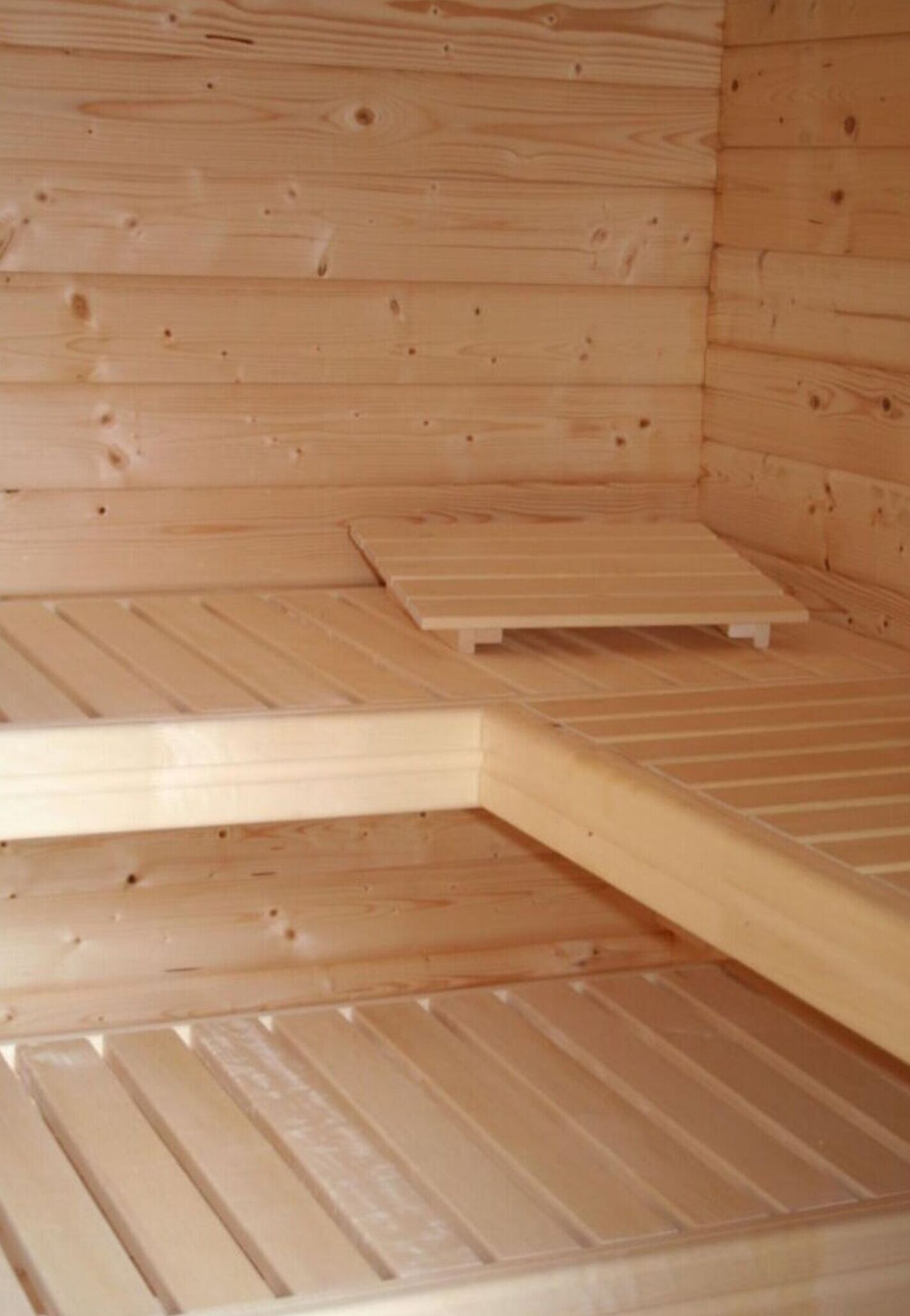 A wooden sauna with benches and a sloped floor.